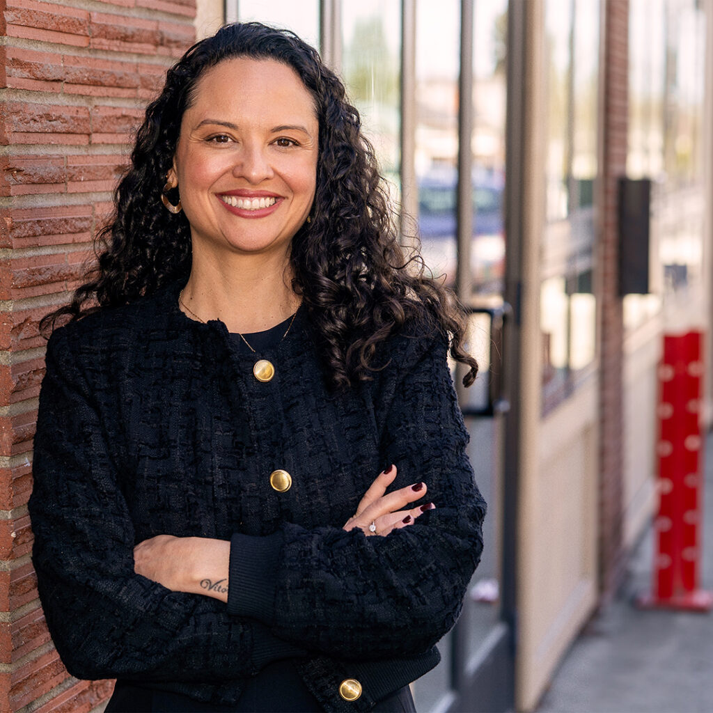 Brazilian woman, smiling, standing in front of a building in Spokane